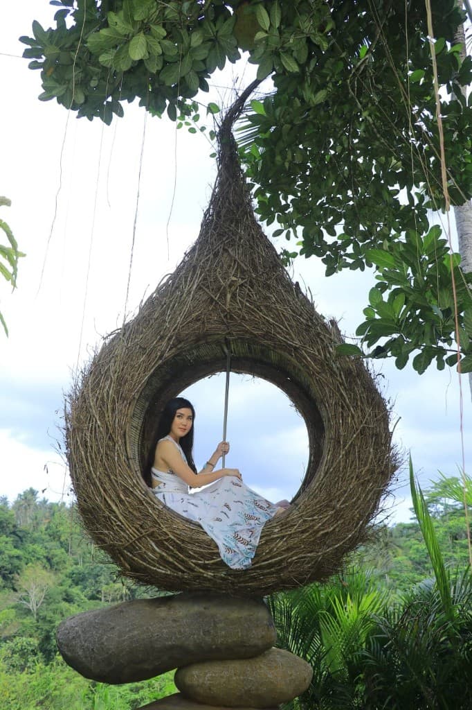 A guest in a feathered white dress in the bird nest overlooking the Tegallalang valley