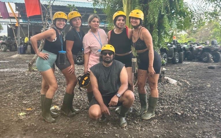 A group in helmets and rubber boots, covered in mud after the ATV ride