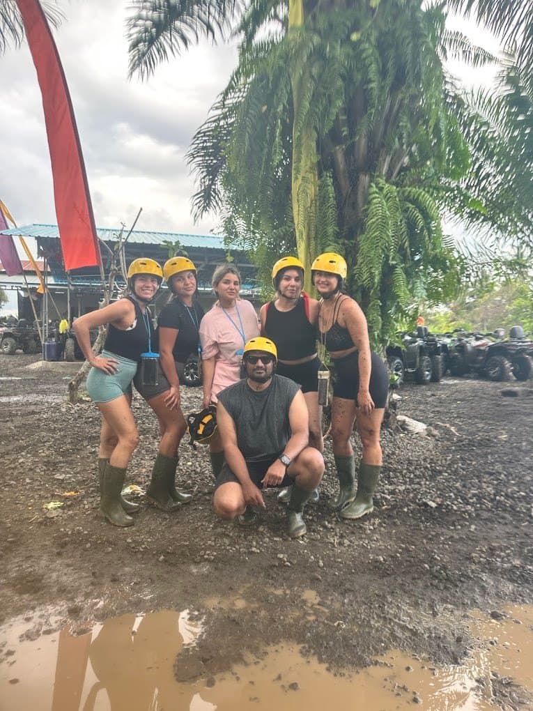 A group in helmets and rubber boots, muddy after the ATV ride