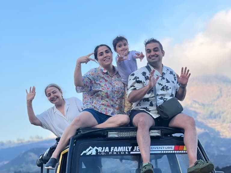 Three generations of a family, including a toddler, waving from the roof of their private Batur jeep above the lava field