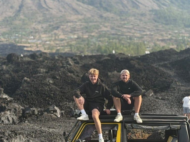 Two guests on a yellow jeep roof in the Batur lava field, before the hot spring on the lake shore