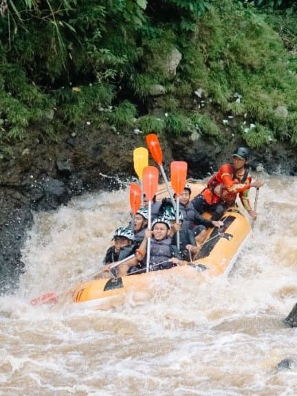 A raft dropping through white water next to the canyon wall