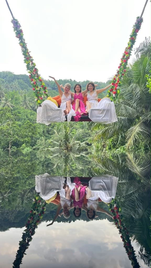 Three guests in flowing dresses on the flower-draped hanging sofa swing at Swing Heaven