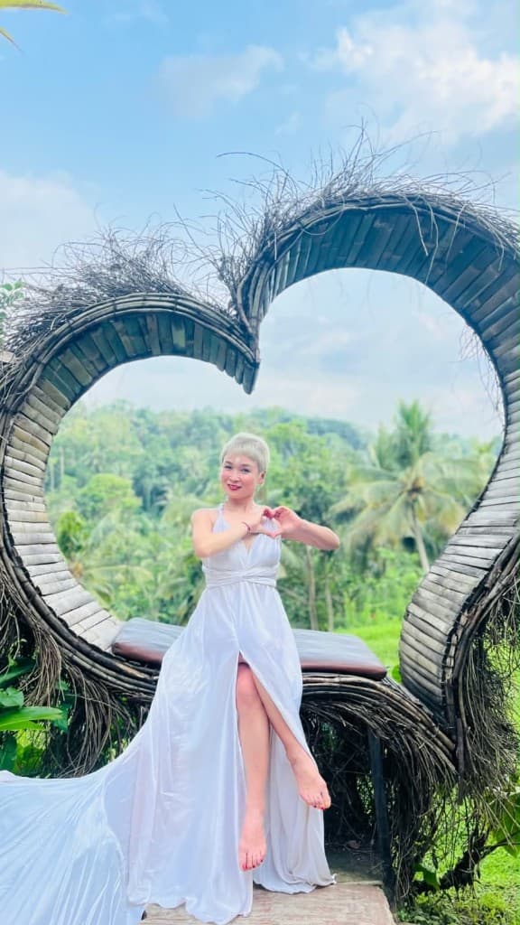 A guest in a white dress posing in the heart nest photo frame at Swing Heaven Bali