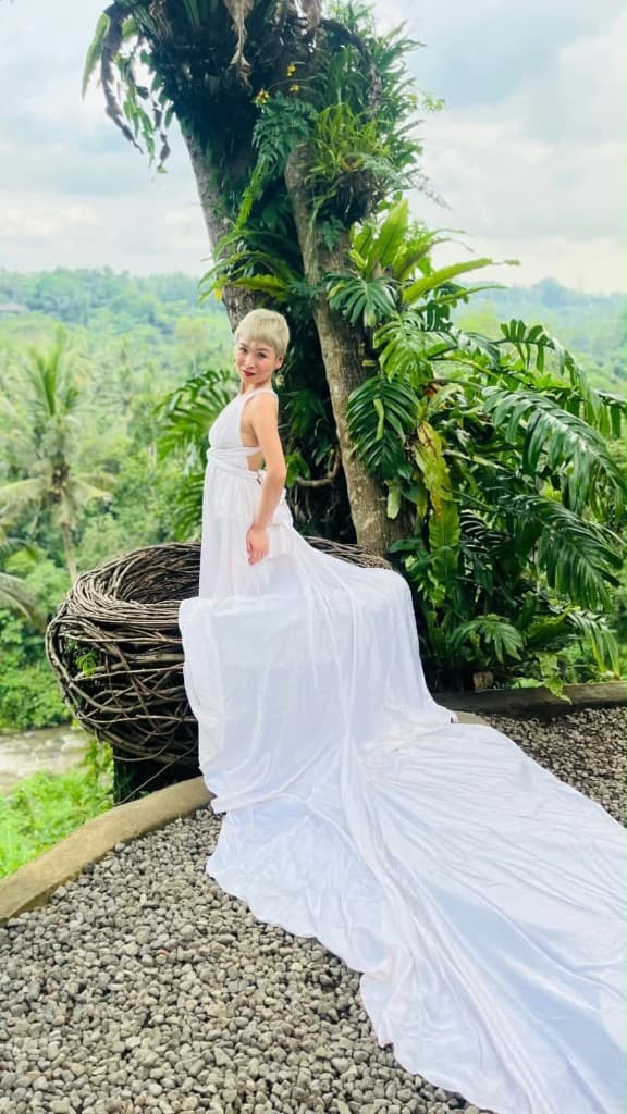 A guest in a long white flying dress in a woven nest — what to wear for Bali swing photos