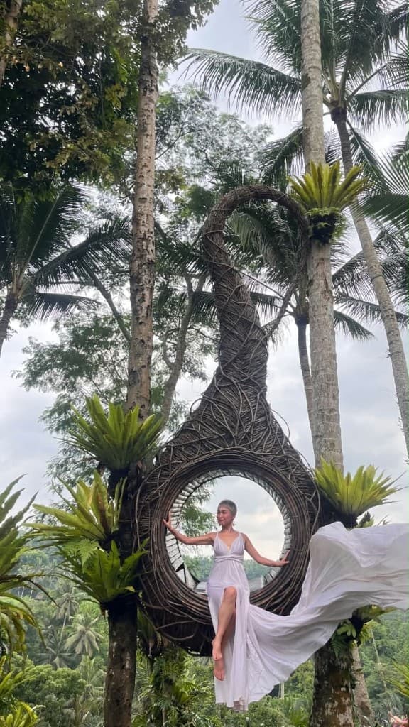 A guest in a white flying dress in the onion nest overlooking the jungle valley at Swing Heaven Bali