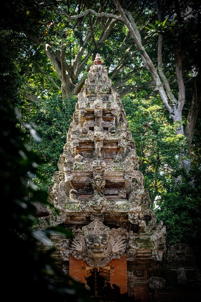 A carved stone Balinese temple gate rising through jungle trees