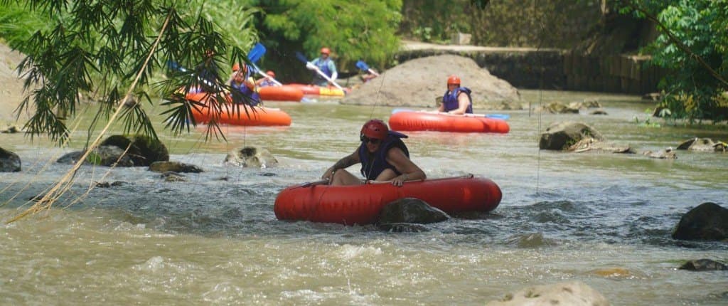 Des voyageurs en casque rouge et gilet de sauvetage descendent une rivière rocheuse sur des bouées rouges